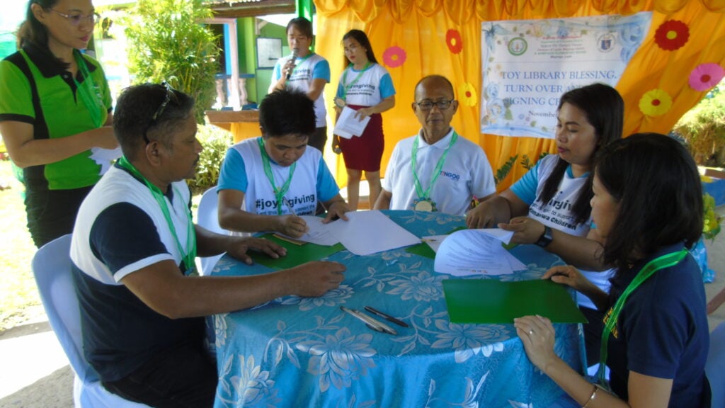 Picture of people sitting in a table signing documents